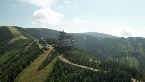180-degrees-orbit-aerial-shot-of-a-sky-walk-tower-attraction-in-Dolni-Morava,-Czech-Republic-and-a-nearby-MTB-bicycle-trail