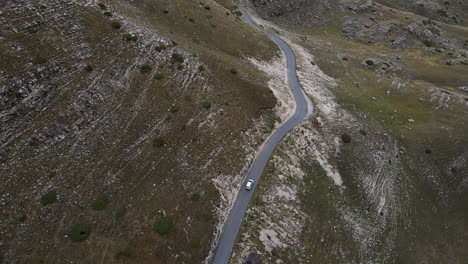 Drohnenaufnahme-Eines-Autos,-Das-Durch-Die-Berge-Mit-Felsen-In-Montenegro-Fährt