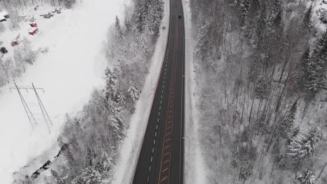 Winter-Highway-Through-Snowy-Forest---aerial-drone-shot