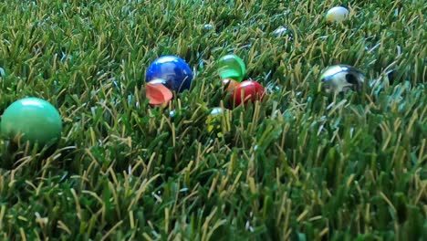 Close-up-of-a-game-of-marbles-that-hit-each-other-in-slow-motion,-bouncing-and-spinning-on-grass