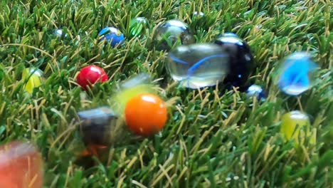 Colourful-marbles-land-and-collide-during-a-game-on-artificial-green-grass