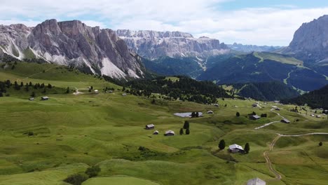 Seceda-and-Val-Gardena-Valley-at-South-Tyrol,-Italian-Alps,-Dolomites,-Italy---Aerial-Drone-View-of-the-Mountains-and-Cabins