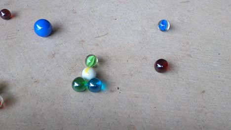 Close-up-shots-of-colorful-marbles-hitting-on-a-grey-concrete-floor
