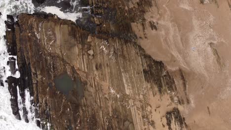 Aerial-birds-eye-shot-of-waves-flooding-spectacular-old-rocks---Beautiful-pattern-texture-from-above---La-Pedrera,Uruguay