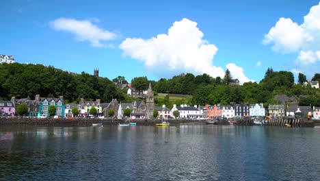 White-clouds-move-slowly-behind-the-hillside-of-the-pretty-village-of-Tobermory-as-small-ripples-pass-in-the-rippling-water-in-the-foreground