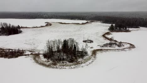 Aerial-drone-view-of-a-frozen-meadow-next-to-lakes-in-winter