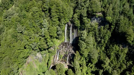 Close-up-of-a-double-waterfall-hidden-in-the-forest-on-a-sunny-day---drone-shot