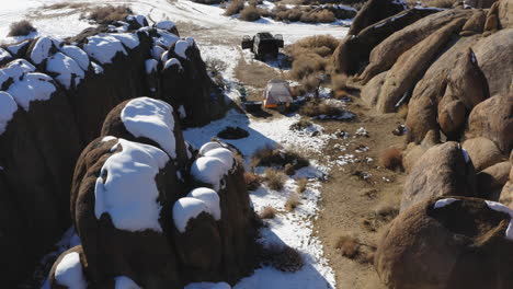 Aerial-view-of-all-terrain-car-and-a-tent-in-Alabama-Hills-snow-covered-granite-rock-landscape