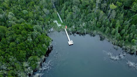 Aerial-orbit-of-a-dock-hidden-in-a-forest-with-crystal-clear-water-allowing-to-see-the-trees-inside-it---drone-shot
