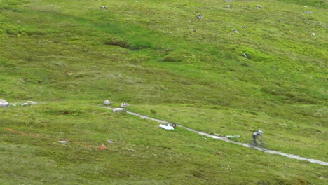 Zwei-Mountainbiker-Fahren-Mit-Hoher-Geschwindigkeit-über-Den-Grauen-Schotterweg-Zwischen-Den-Steinen-Und-Dem-Grünen-Rasen-Des-Höchsten-Berges-Schottlands,-Ben-Nevis,-Hinab