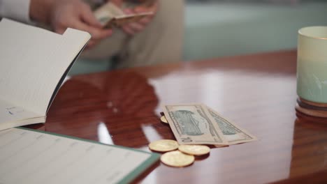 Man-throwing-dollar-bills-on-a-wooden-table-with-golden-bitcoins