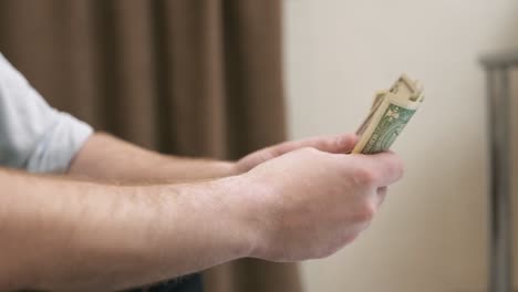 Close-up-shot-of-hands-of-businessman-counting-hundred-dollar-bills-at-home