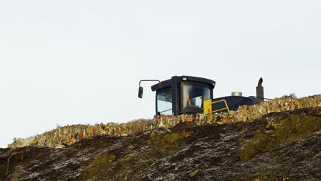 Stack-of-different-types-of-large-garbage-dump,-plastic-bags,-and-landfill-full-of-trash,-environmental-pollution,-yellow-truck-dump-waste-products-polluting-in-a-dump,-distant-medium-shot