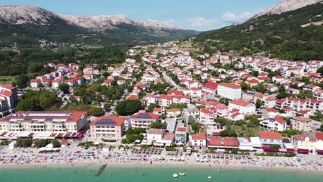 Aerial-Drone-View-of-Baška-Beach,-Krk-Island,-Croatia---Valley,-Town,-Mountains,-Tourists-and-Blue-Sea-at-a-Summer-Sunny-Day