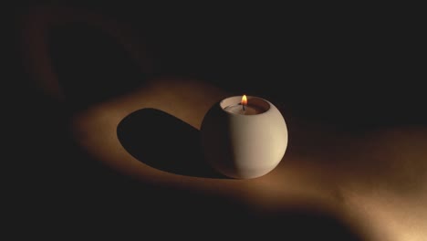 Eine-Runde-Kerze-Isoliert-Auf-Schwarzem-Hintergrund-Mit-Einem-Kleinen-Lichtstrahl,-Der-Einen-Hoffnungsschimmer-Zeigt