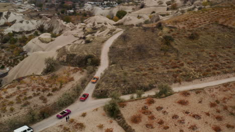 Aerial-View-Of-Van-And-Vintage-Convertible-Cars-Driving-Through-Dirt-Road-In-Cappadocia,-Turkey