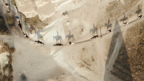 Top-View-Of-Turkish-Men-Riding-On-Horses-Passing-By-A-Curve-Dirt-Road,-Cappadocia,-Turkey