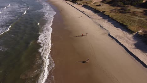 Woman-walking-on-Playa-Grande-beach-with-dog,-Punta-del-Diablo-in-Uruguay