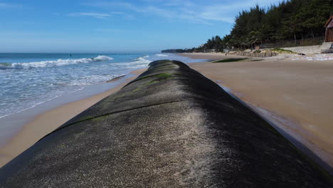 Low-drone-pullback,-Geotube-laid-down-on-beach-shore-to-prevent-rising-sea-levels-caused-by-climate-change-global-warming