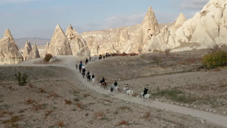 Turkish-Men-And-Caravan-Of-Horses-Passing-Across-The-Cappadocia-Landscapes,-Turkey