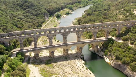 Pont-du-Gard-aqueduct-bridge-built-by-the-Romans-in-the-first-century-southern-France-crossing-the-Gardon-river,-Aerial-pan-left-shot