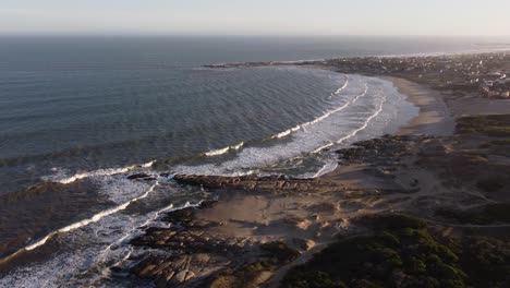 Schöne-Luftaufnahme,-Die-Playa-Del-Rivero-Während-Der-Sonnenuntergangszeit-In-Punta-Del-Diablo,-Uruguay-Zeigt---Wellen-Des-Ozeans,-Die-Sandstrand-Und-Küstenlinie-Erreichen
