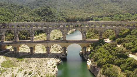 Pont-du-Gard-Roman-built-aqueduct-in-southern-France-crossing-the-Gardon-river,-Aerial-pedestal-up-shot