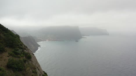 Revealing-Aerial-View,-Hills-and-Misty-Coastline-of-Madeira-Island,-Portugal,-Rainy-Clouds-and-Skyline,-Drone-Shot