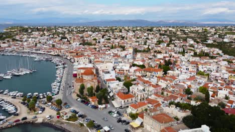 Aerial-drone-view-and-view-of-yachts-in-the-main-marine-at-Aegina-Island,-with-Ekklisia-Isodia-Theotokou-Church-in-Aegina-town-and-moored-old-fshing-boats,-Aegina-Island,-Greece