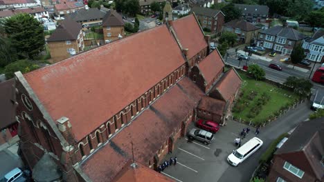 Aerial-view-wedding-ceremony-vehicles-arrive-at-charming-English-village-church