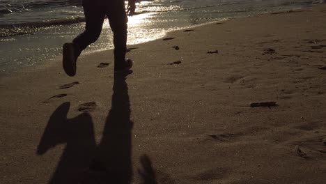 Kind-Silhouettiert-Schatten,-Der-Bei-Sonnenaufgang-Zeitlupe-über-Den-Goldenen-Sandstrand-Von-Portugal-Läuft