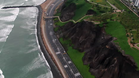 Seaside-highway-alongside-the-beach-in-Miraflores-Peru-next-to-a-cliff,-drone-shot