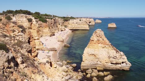 Aerial-Drone-View-of-Marinha-Beach-at-Algarve,-South-Portugal---Coastline,-Cliffs,-Tourists-and-Boat