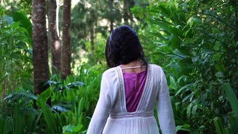 Following-a-woman-walking-into-the-forest-while-touching-and-caressing-the-lush-vegetation-and-the-green-leaves