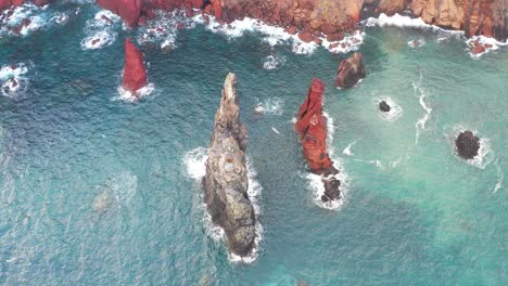 Aerial-View,-Sharp-Rock-Formation-Under-Cliffs-Above-Atlantic-Ocean,-Picturesque-Coastline-of-Madeira-Island,-Portugal,-Drone-Shot