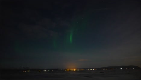 Panorama-shot-of-emerging-Aurora-Borealis-over-city-of-Reykjavik-during-night-in-Iceland