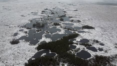 High-up-aerial-drone-view-of-barren-bog-landscapes-with-a-group-of-frozen-lakes