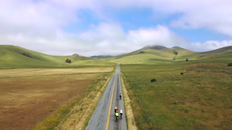 Scenic-Landscape-with-Cyclists-Riding-on-Road-through-Mountains---aerial-drone-shot