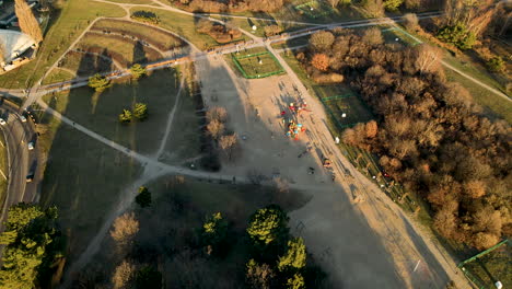 Children-playing-at-public-playground-at-sunset-in-Ronald-Reagan-Park,-Gdansk,-Poland---aerial-top-view