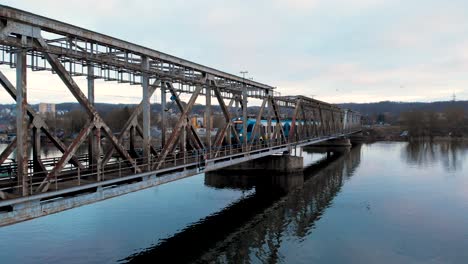 Local-Train-Traveling-At-Railway-Bridge-Over-Calm-River-Near-Szczecin,-Poland