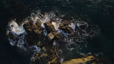 Ocean-tide-waves-slam-against-rocks-during-sunset