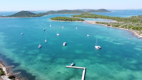 Kornati-Islands-in-Dalmatia,-Croatia---Aerial-Drone-View-of-the-Bay-with-Turqouise-Sea-and-Sail-Boats