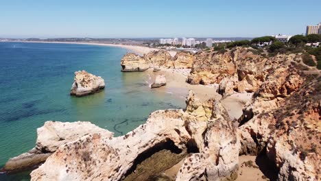 Praia-dos-Tres-Irmaos-Beach,-Algarve,-Portugal---Aerial-Drone-View-of-the-Coastline-with-Rocky-Cliffs,-Tourists-and-Hotels