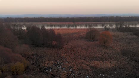 Drone-Flying-Over-Countryside-Landscape-Revealing-Lake-At-Sunset-During-Autumn-In-Poland