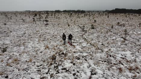 Aerial-drone-view-of-a-couple-walking-with-snowshoes-in-a-barren-bog-landscape