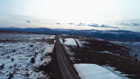 Drone-shot-rising-up-over-a-long-highway-with-mountains-and-valleys