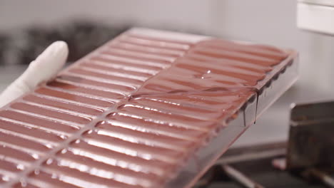 Chocolate-Stick-Production,-Making-Chocolate-Bars,-Smoothing-Down-Liquid-Chocolate-in-Plastic-Mold