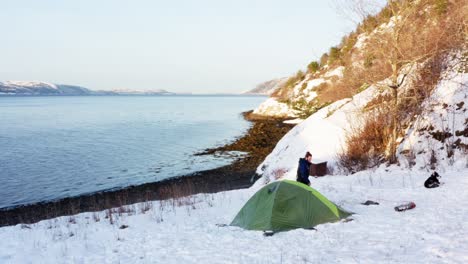 Aerial-View-Of-Camper-Walking-Outside-His-Tent-At-Winter