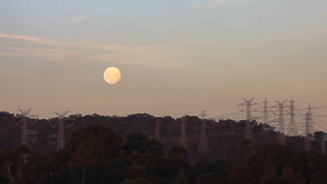 Full-moon-sitting-above-silhouetted-power-lines-above-providing-power-to-surrounding-suburban-areas