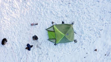 Camper,-Der-Im-Winter-Auf-Seinen-Alaskischen-Malamute-Hund-Zugeht,-Der-Auf-Schneebedecktem-Boden-Liegt